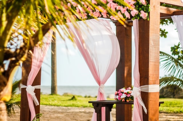9 Tips to Make Your Wedding More Eco-Friendly, a gazebo draped with thin curtains and a flower border.