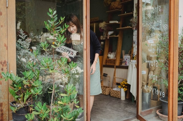 A woman tending to a plant in a flower shop.