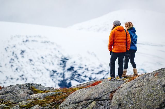 “Experience Gifts” for Adventurous Couples, a couple standing on a mountain, looking at a taller, snow covered mountain.