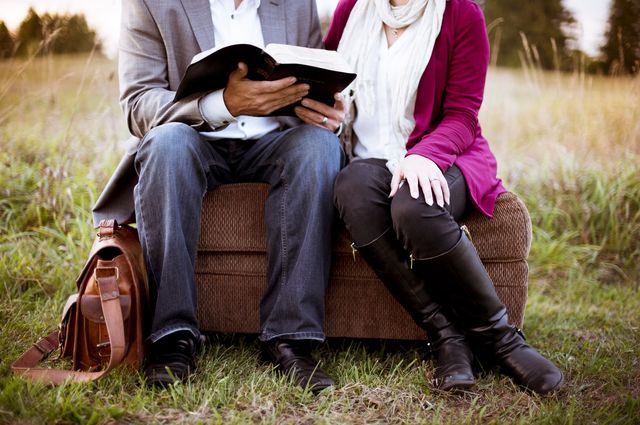“Experience Gifts” for Adventurous Couples, a couple sitting on a bench looking at a book.